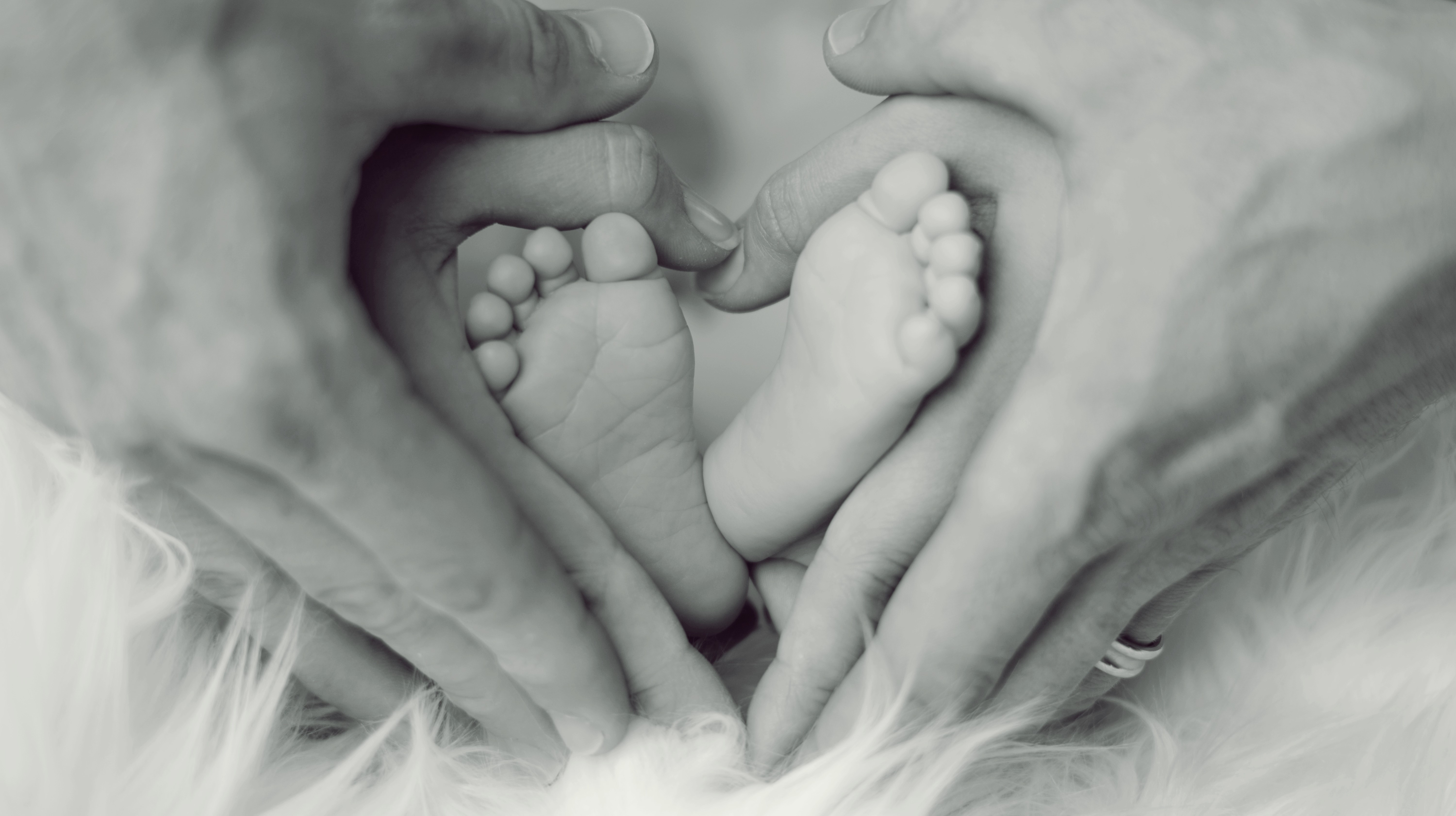 Les mains en coeur d'un homme entourent celles d'une femme qui entourent les pieds de leur bébé, conception, hygiène de vie, naturopathe rennes