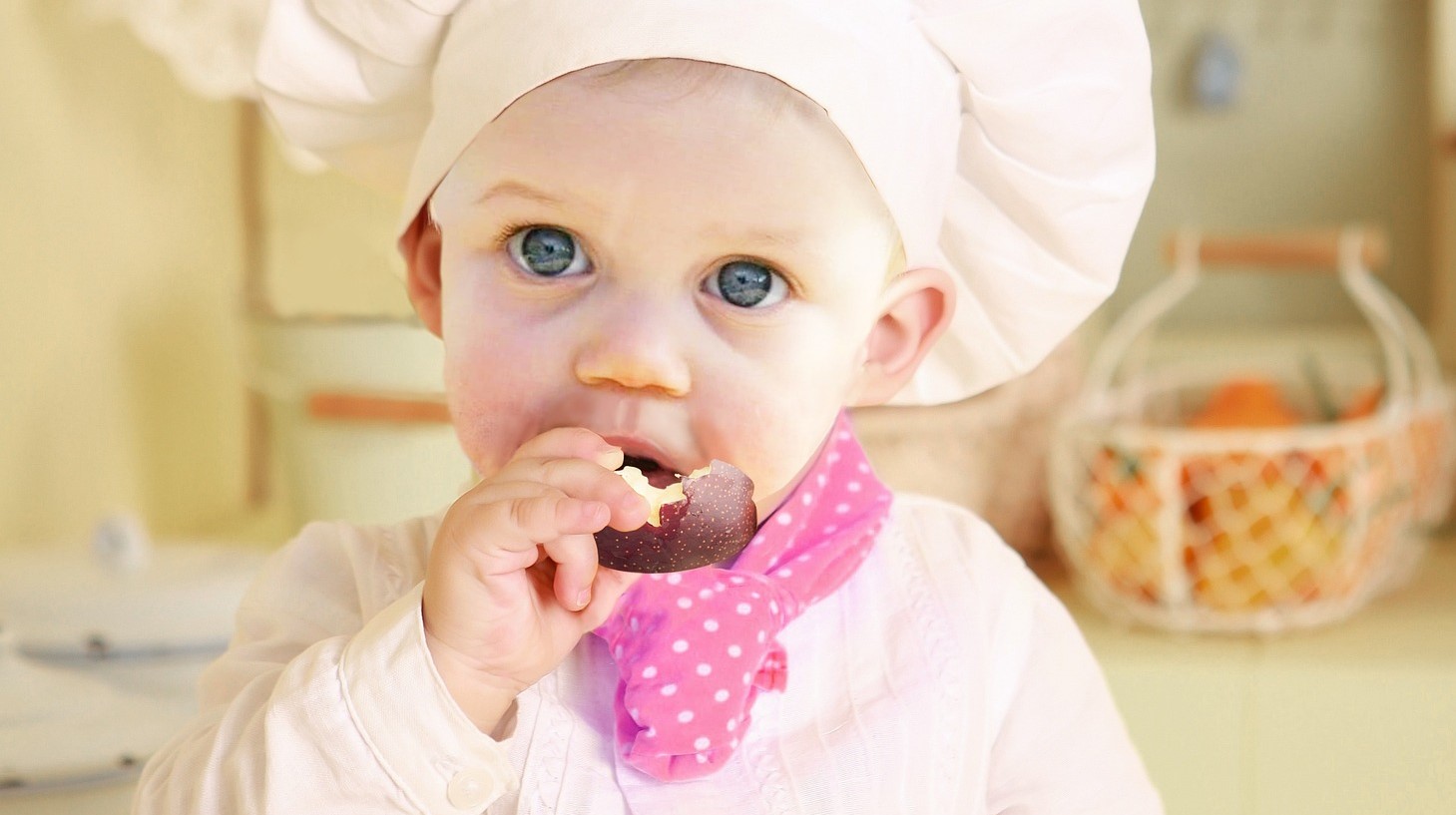 Enfant en toque de chef qui se régale d'une pomme