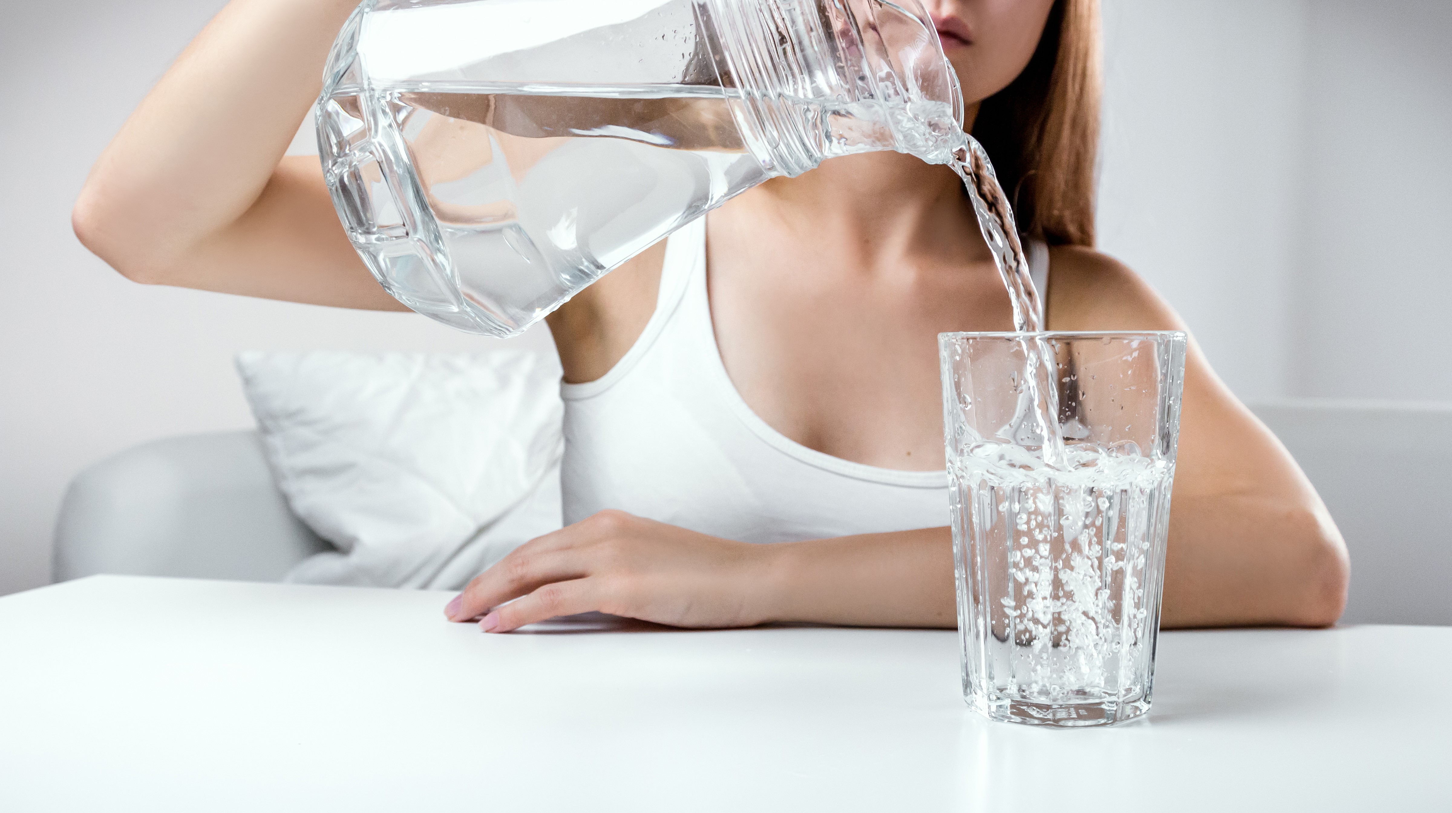 Jeune femme se servant un grand verre d'eau, hygiène de vie, naturopathe rennes